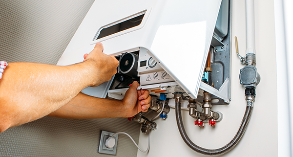man repairing a wall-mounted heater with visible pipes and controls in a residential setting maintenance tips for efficient operation of 6 heaters