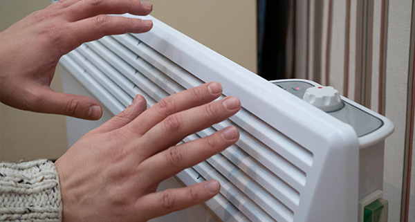 hands adjusting a white heater with controls in a warm indoor setting essential for comfort and warmth