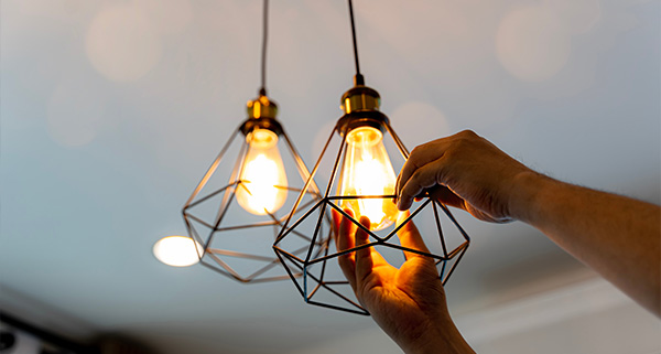 hand adjusting modern pendant light fixture with two glowing bulbs in a contemporary setting featuring a stylish design and perfect for illuminating spaces with twelve stunning watts