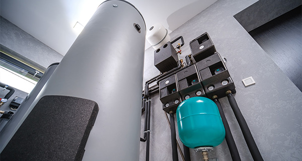interior view of plumbing system featuring a large gray water tank and turquoise pressure vessel indicating modern water solution technology