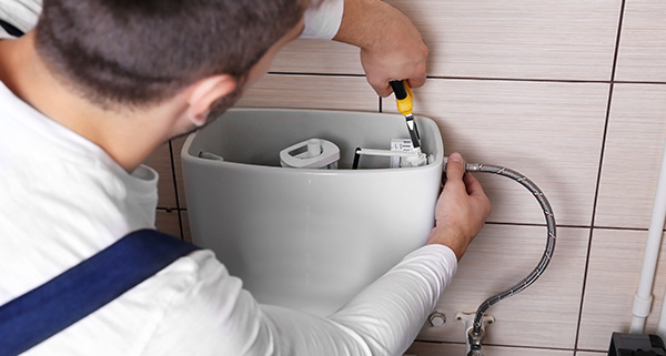 person wearing yellow gloves fixing a kitchen faucet using a wrench home maintenance tips for ten solutions